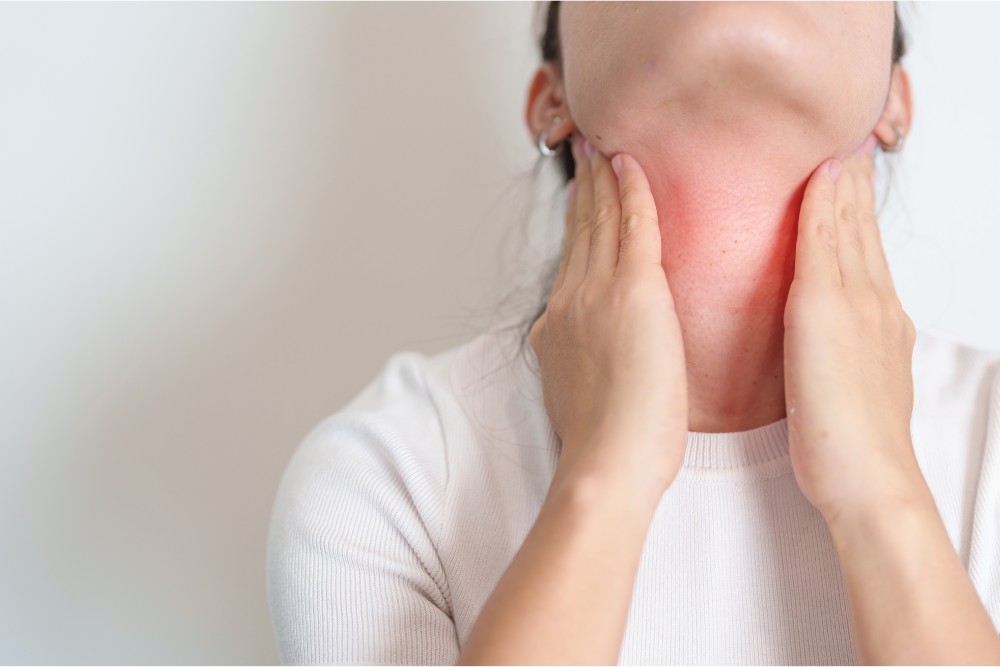 Woman having pain in throat suffering from grave's disease.