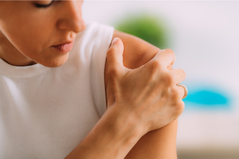 Young girl having shoulder pain because of the knot in the muscle.