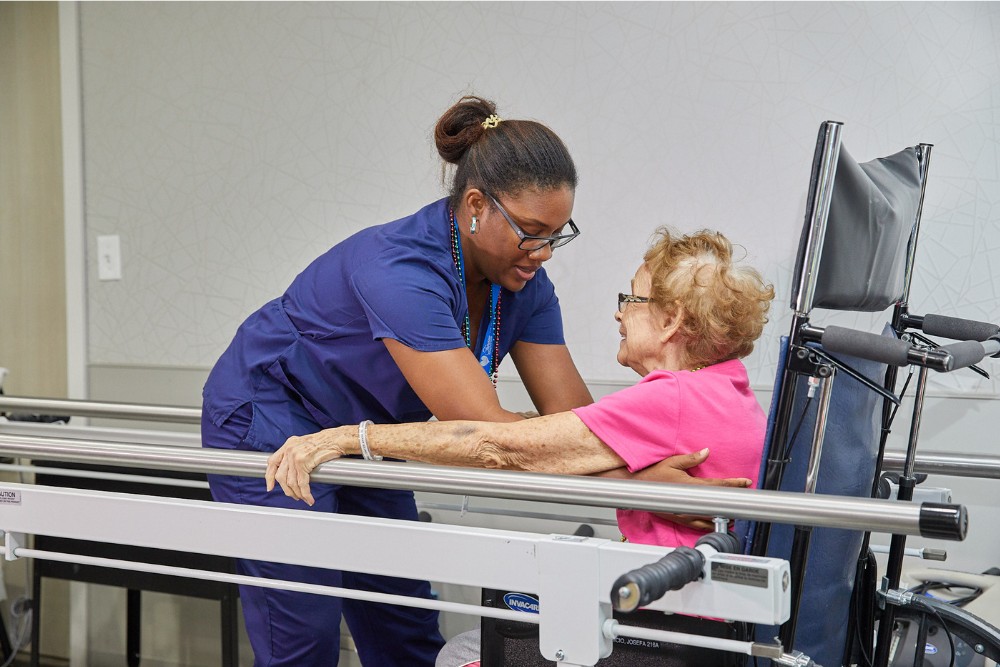 Healthcare professional assisting elderly woman with orthopedic rehabilitation exercises for improved mobility and recovery.