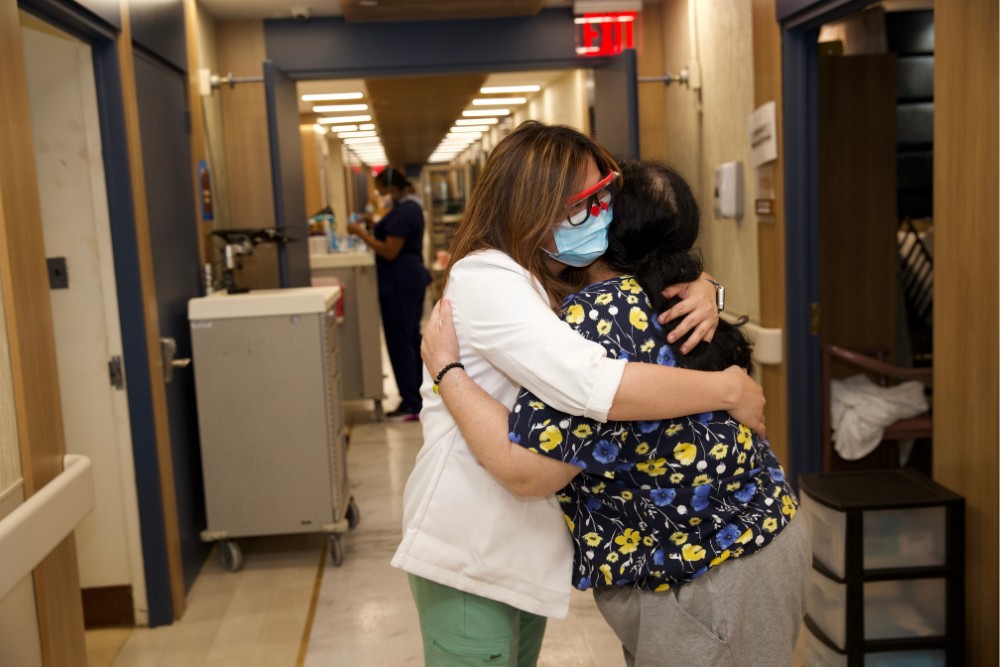 Healthcare worker hugging a patient in a hallway, showcasing compassion and connection as a way to combat the dangers of depression in a care facility.